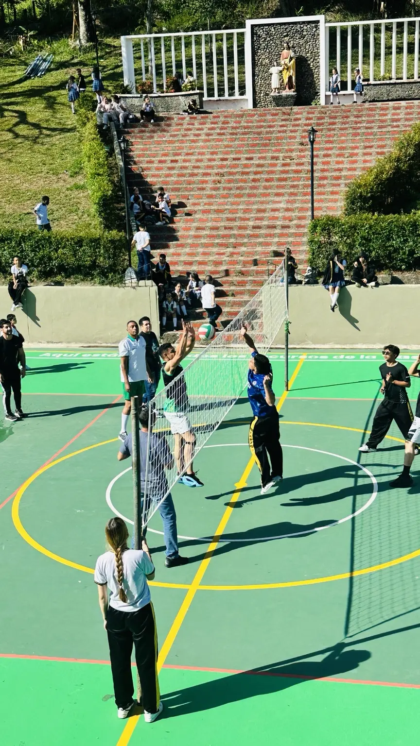 Estudiantes de grado 11 y profesores disputando una jugada junto a la red